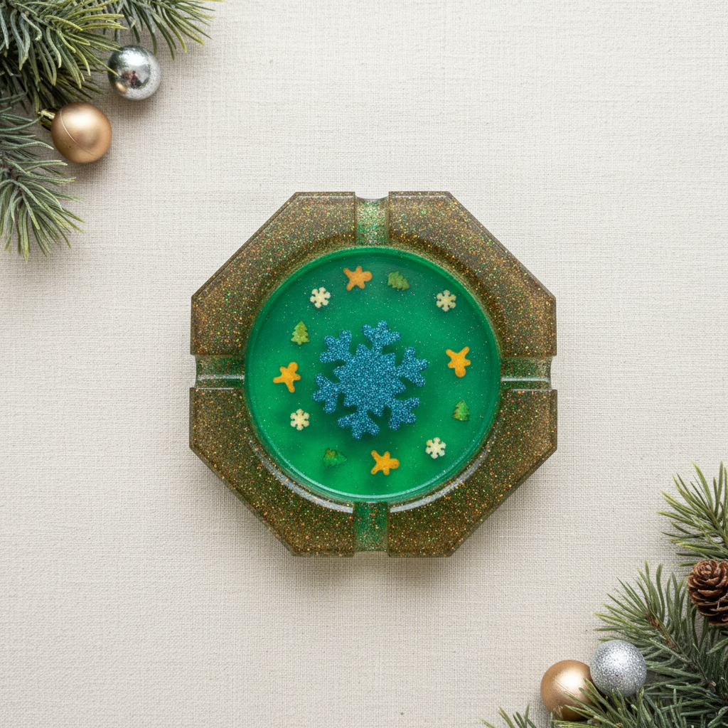 Flat-lay of a handmade bright green translucent octagonal resin ashtray with a metallic blue glitter snowflake, gold glitter rim, and Christmas sprinkle embeds on a light winter surface