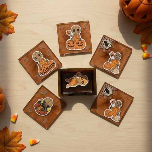 Flat-lay lifestyle photo of a Trick 'r Treat Sam four-piece coaster set with amber-brown resin holder