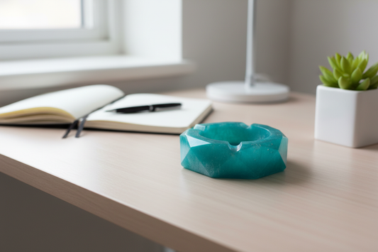 Teal geometric polygon resin ashtray on a wooden desk with a succulent and notebook