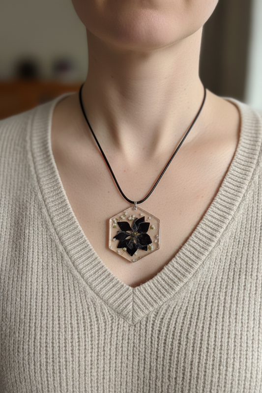 Pansy resin hexagon pendant necklace with black pansy and baby's breath on a black cord being worn