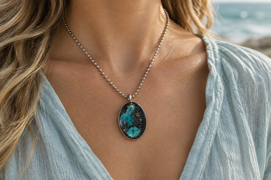 Turquoise baby's breath oval resin pendant necklace being worn in a coastal setting
