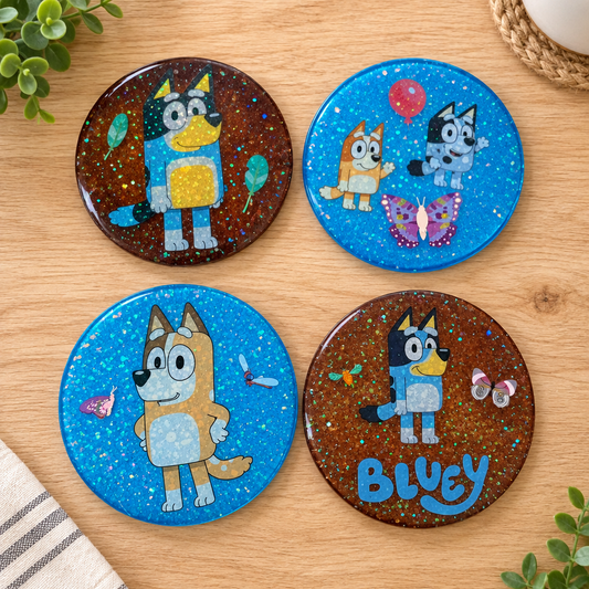 Set of four Bluey character coasters with glitter arranged on a wooden surface