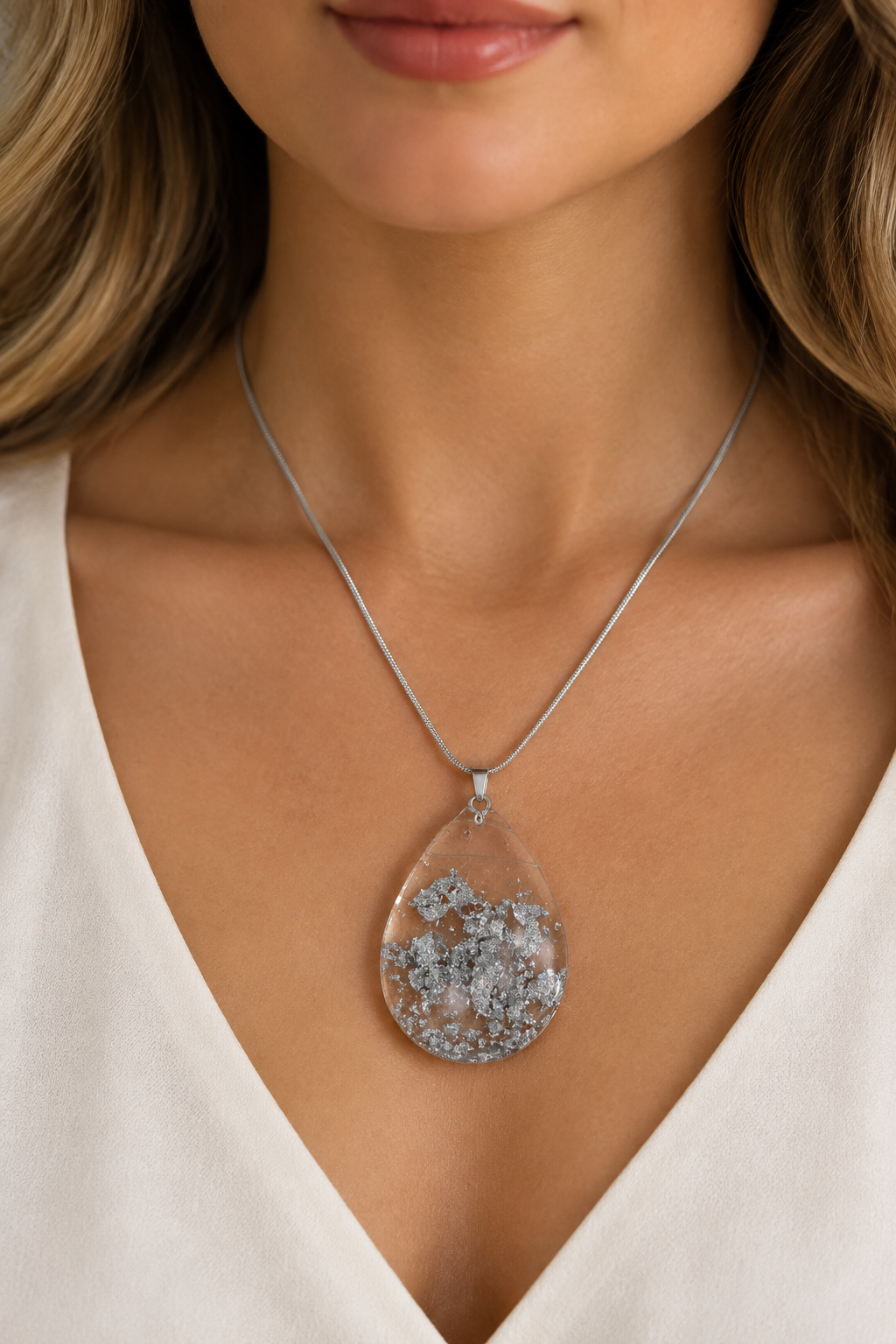 Model wearing sparkling silver teardrop pendant necklace with soft lighting