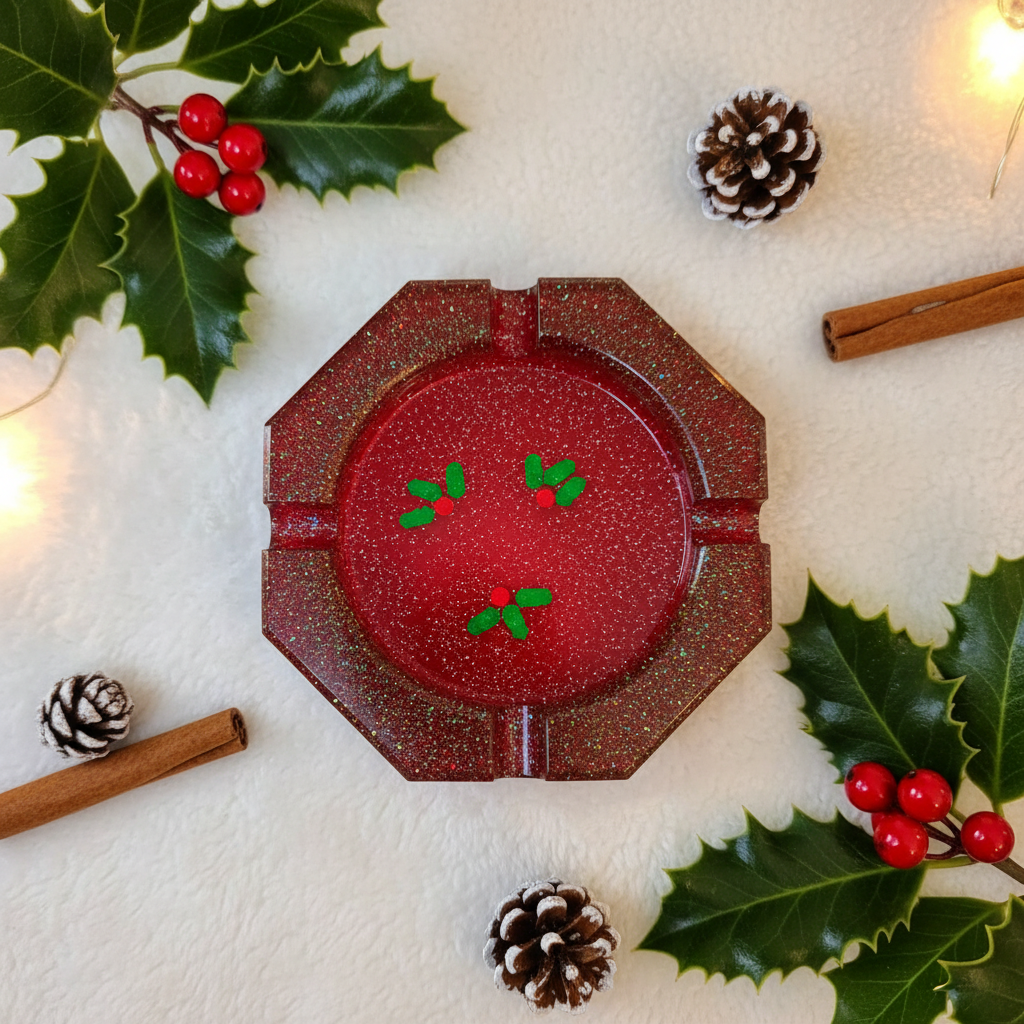 Red glitter octagonal resin ashtray with mistletoe sprinkles shown flat on a white surface with holly and pinecones