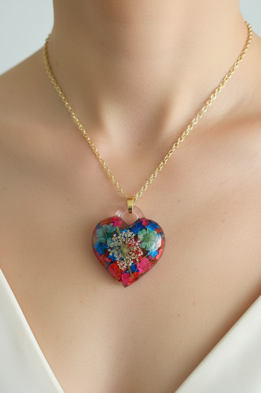 Close-up lifestyle photo of botanical heart resin pendant with wildflowers and confetti worn at collarbone