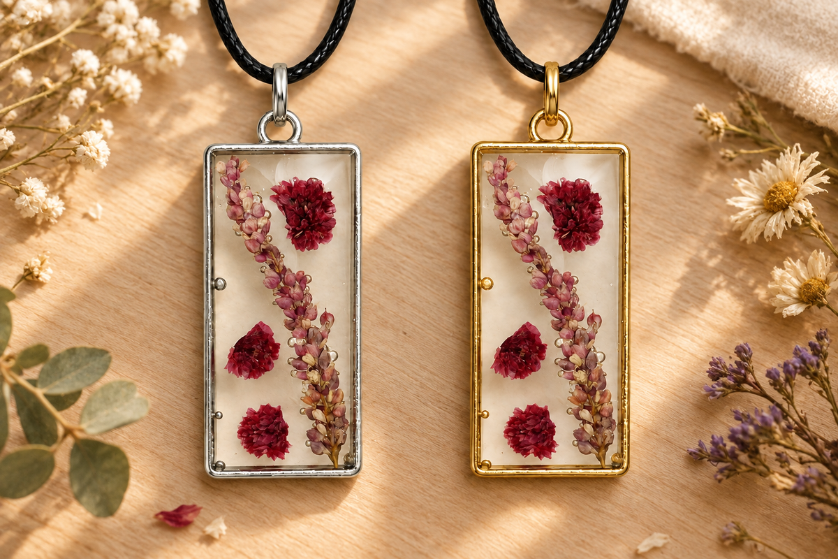 Gold and silver bezel pressed-flower pendant necklaces on a wood surface with dried flowers