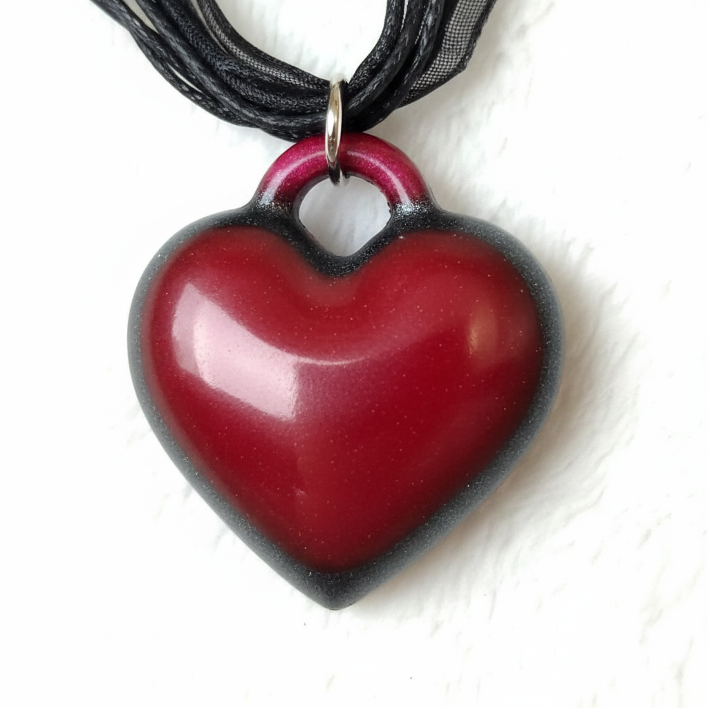 Close-up macro photo of whimsigoth crimson heart resin pendant showing deep red center and black mica gradient edges