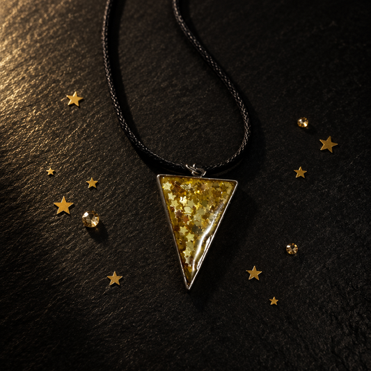Gold glitter star triangle resin pendant necklace on black surface with gold star confetti