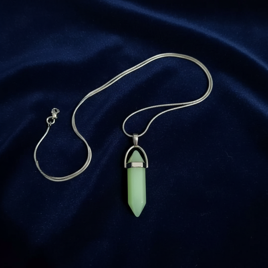Glow-in-the-dark crystal pendant necklace shown flat on dark blue velvet